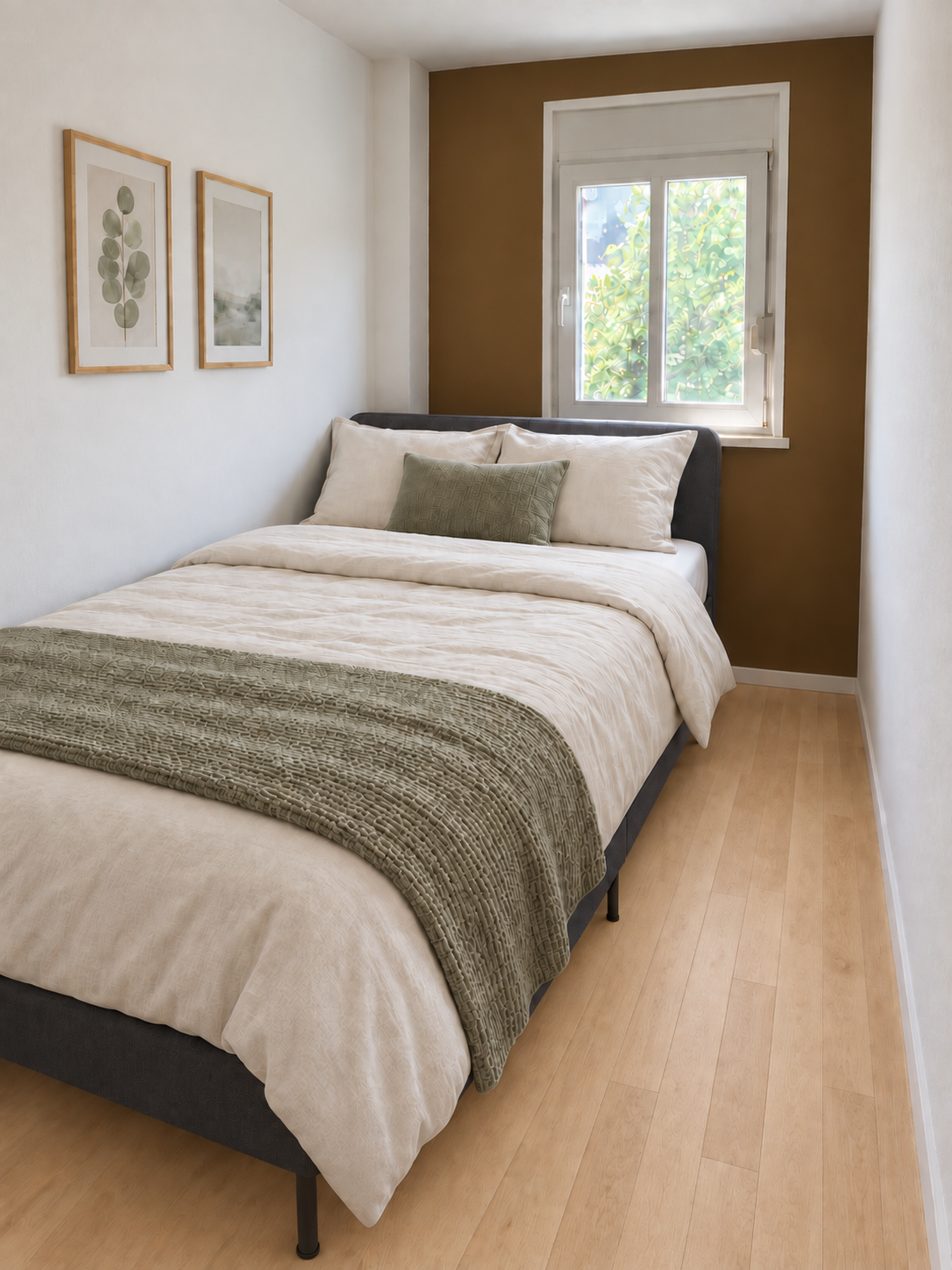 Möbliertes Zimmer mit Doppelbett, weißer Bettwäsche, grüner Decke und Fenster ins Grüne vor einer braunen Akzentwand